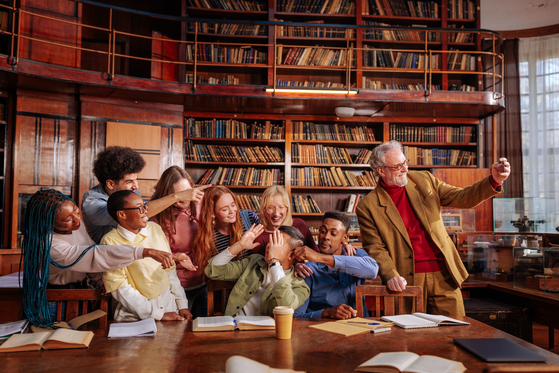 Professor takes selfie with students in library.