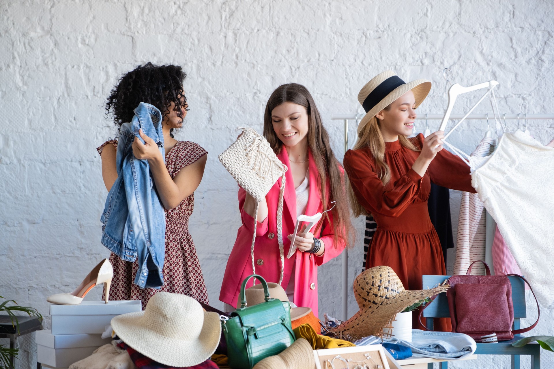 Young women choose things at flea market. Casual clothes, shoes, hats, bags