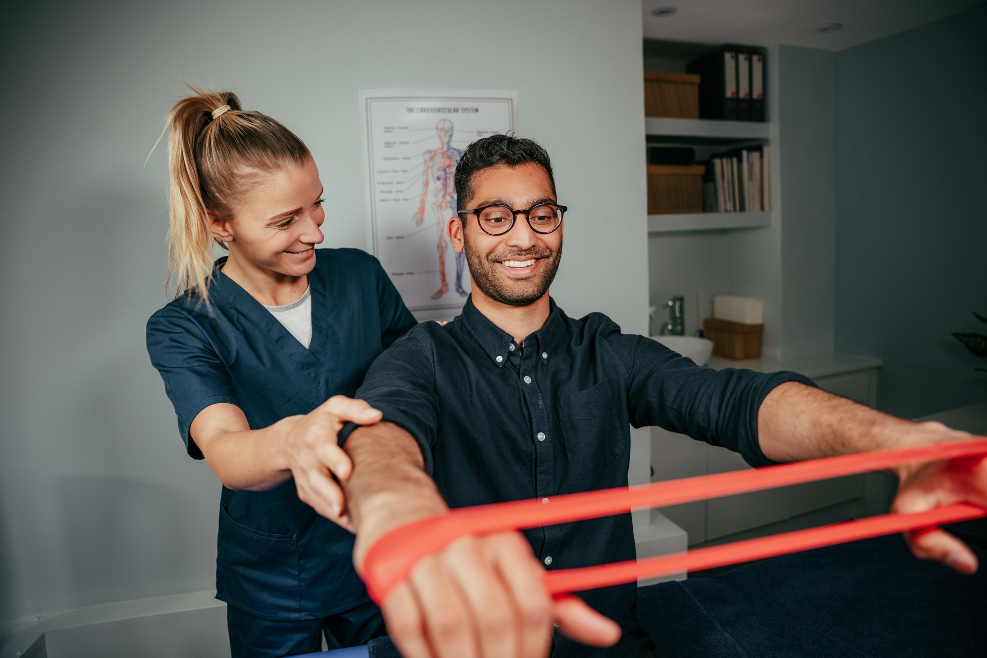 Caucasian female physiotherapist assisting male patient holding resistance band