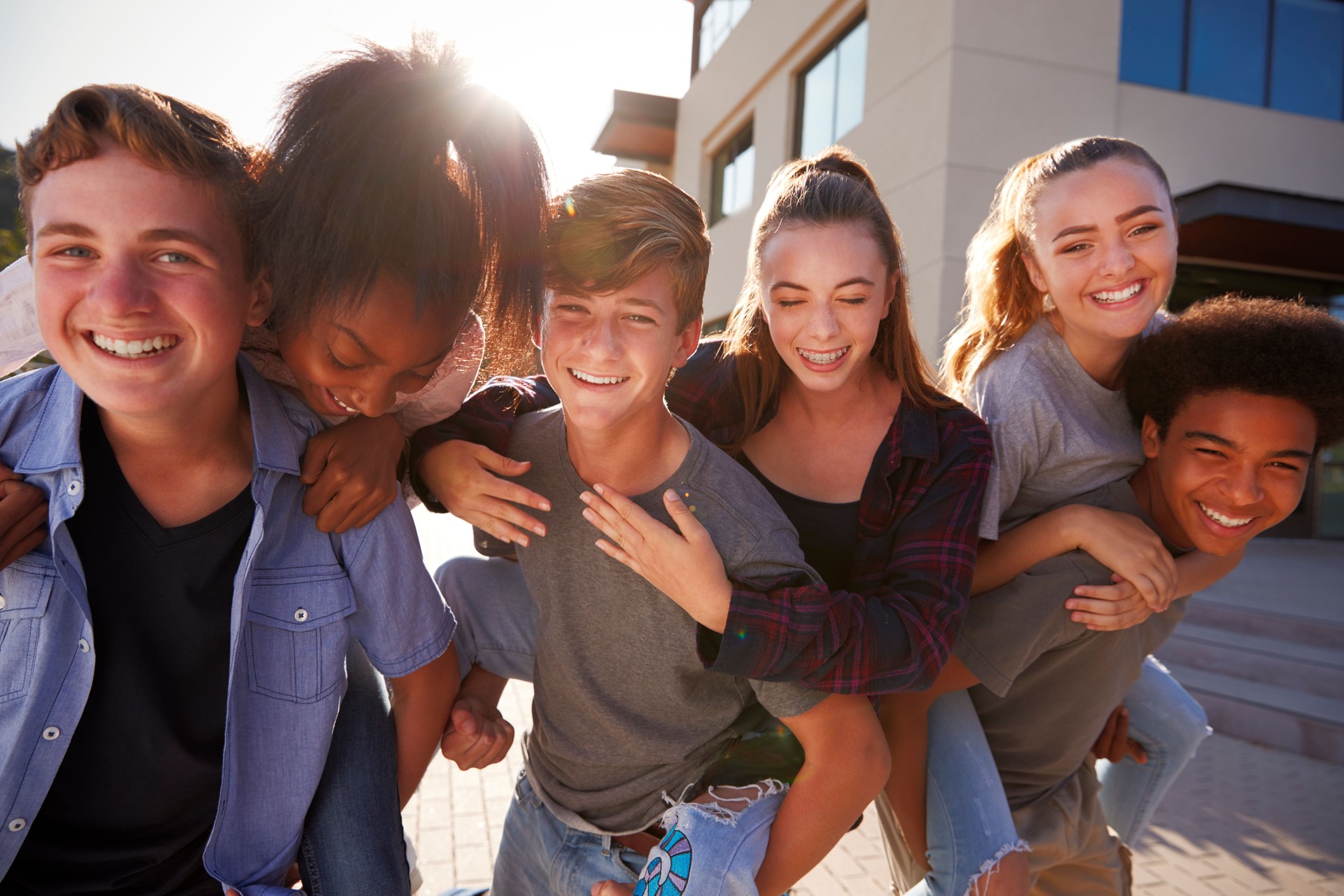 Portrait Of High School Students Giving Each Other Piggybacks College Buildings